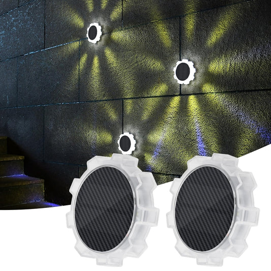 AVANLO zunanje solarne luči Naklikaj.si (komplet 6 kosov, RGB 9 LED, 4 načini osvetlitve, IP65 vodoodporne) oddajajo živahne krožne in sevalne svetlobne vzorce na teksturiranih stenah, ob strani pa so subtilno modro osvetljene stopnice.