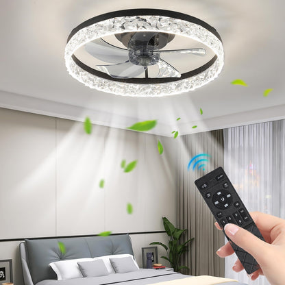 Roka z daljinskim upravljalnikom upravlja Naklikaj.si Stropna LED luč z ventilatorjem in daljinskim upravljanjem - 50 cm, črna. Krožna svetloba in pretok zraka sta vidna, v sveži spalnici z rastlinami in velikimi okni se vrtinčijo zeleni listi.